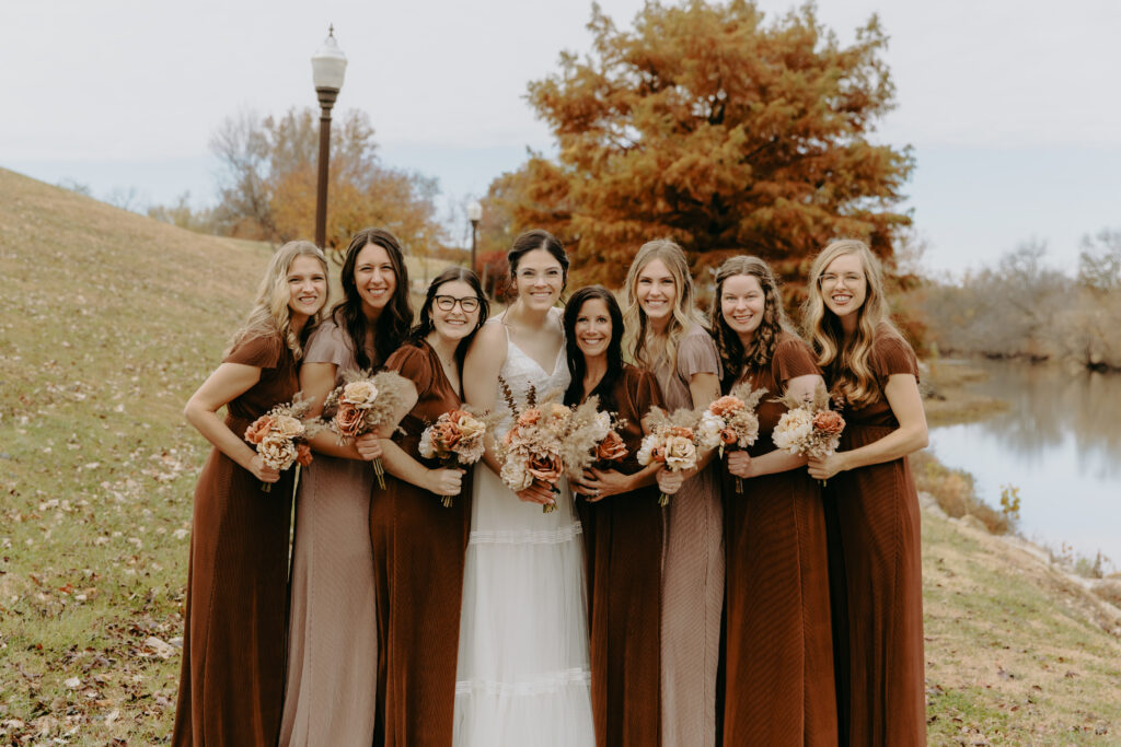 Kansas bride and her bridesmaids posed along the Council Grove, KS Riverwalk in the fall.
